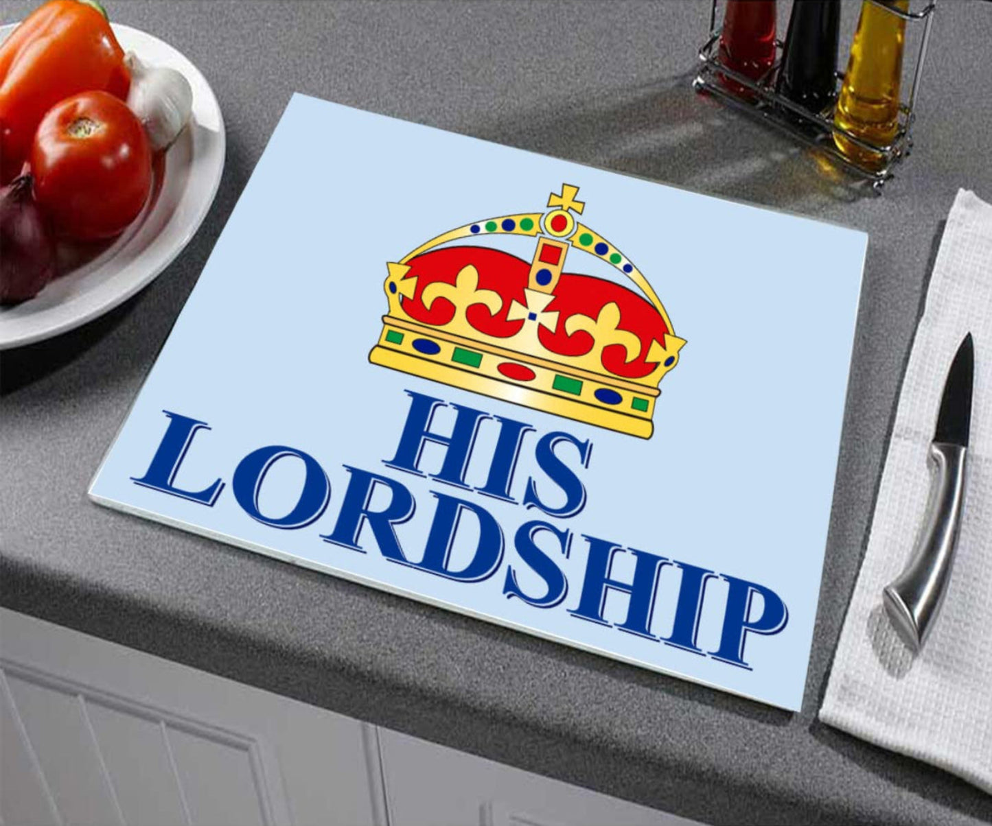 Glass cutting board with a crown design and 'His Lordship' text on a kitchen counter.