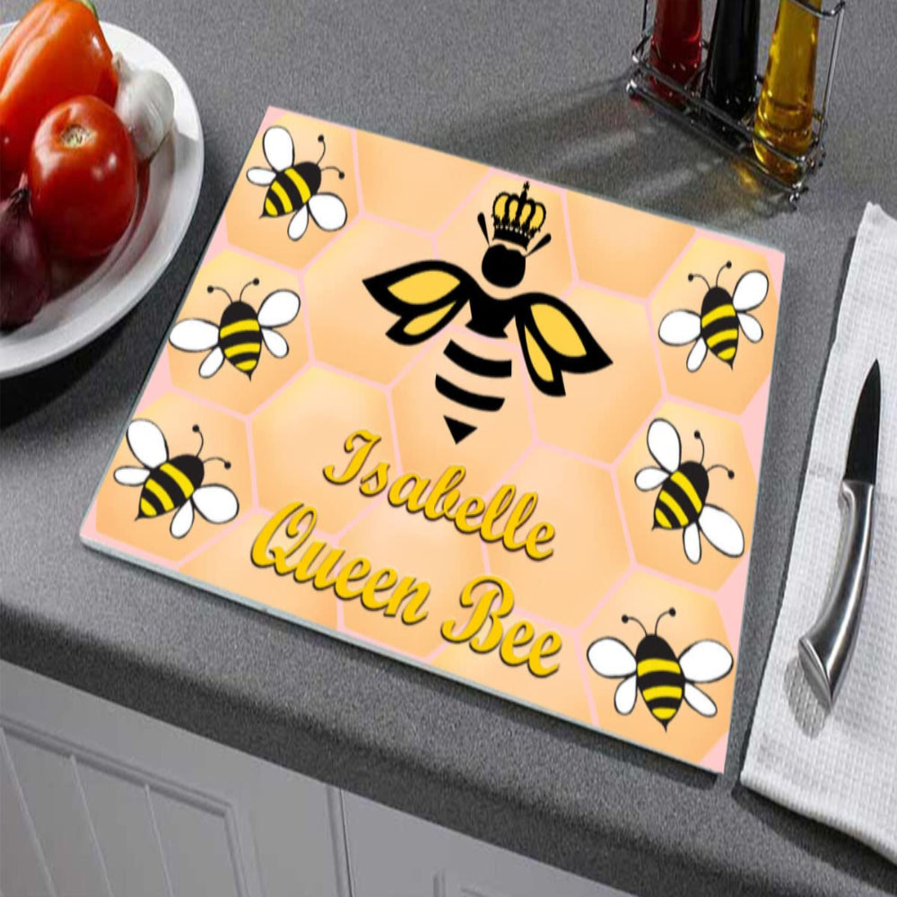 Personalized cutting board with bee design and text on a kitchen counter.