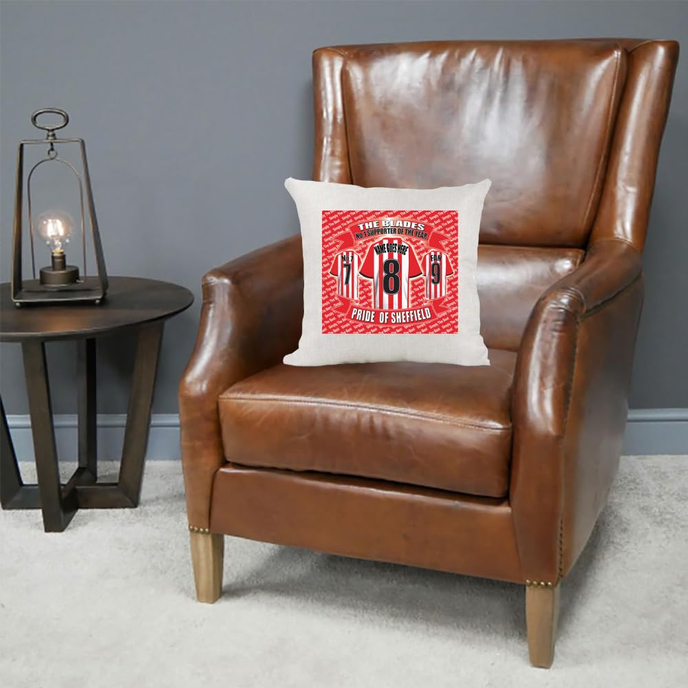 Brown leather armchair with a decorative pillow featuring sports team graphics on a gray background.