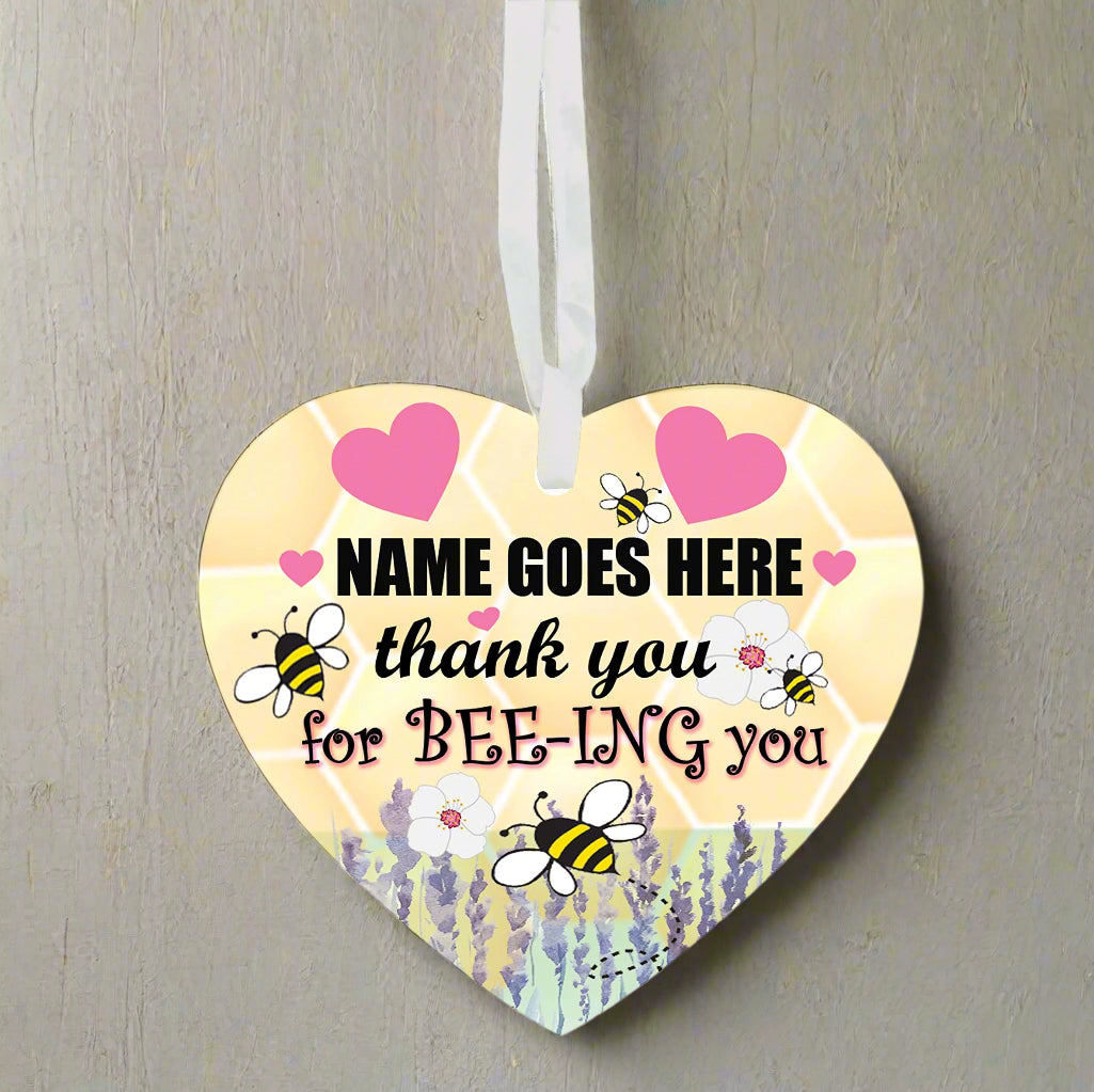 Heart-shaped hanging ornament with bee designs and text on a white background