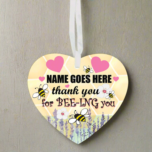 Heart-shaped hanging ornament with bee designs and text on a white background