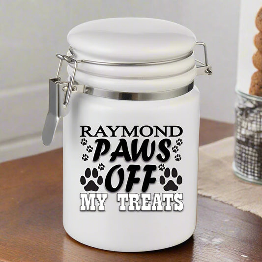 White treat jar with 'Raymond Paws Off My Treats' text and paw prints on a white background