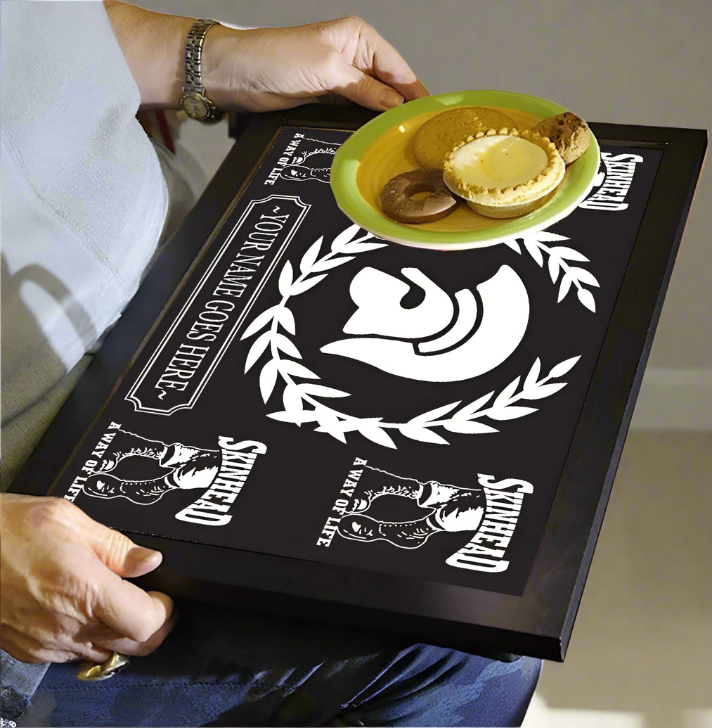 Person holding a black tray with white designs and text, featuring a plate of food.