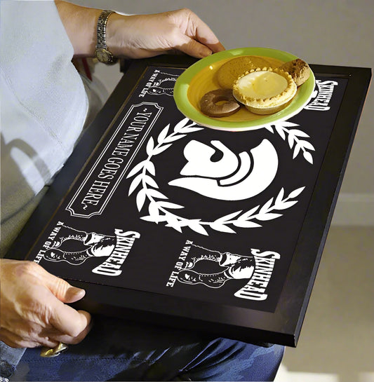 Person holding a black tray with white designs and text, featuring a plate of food.