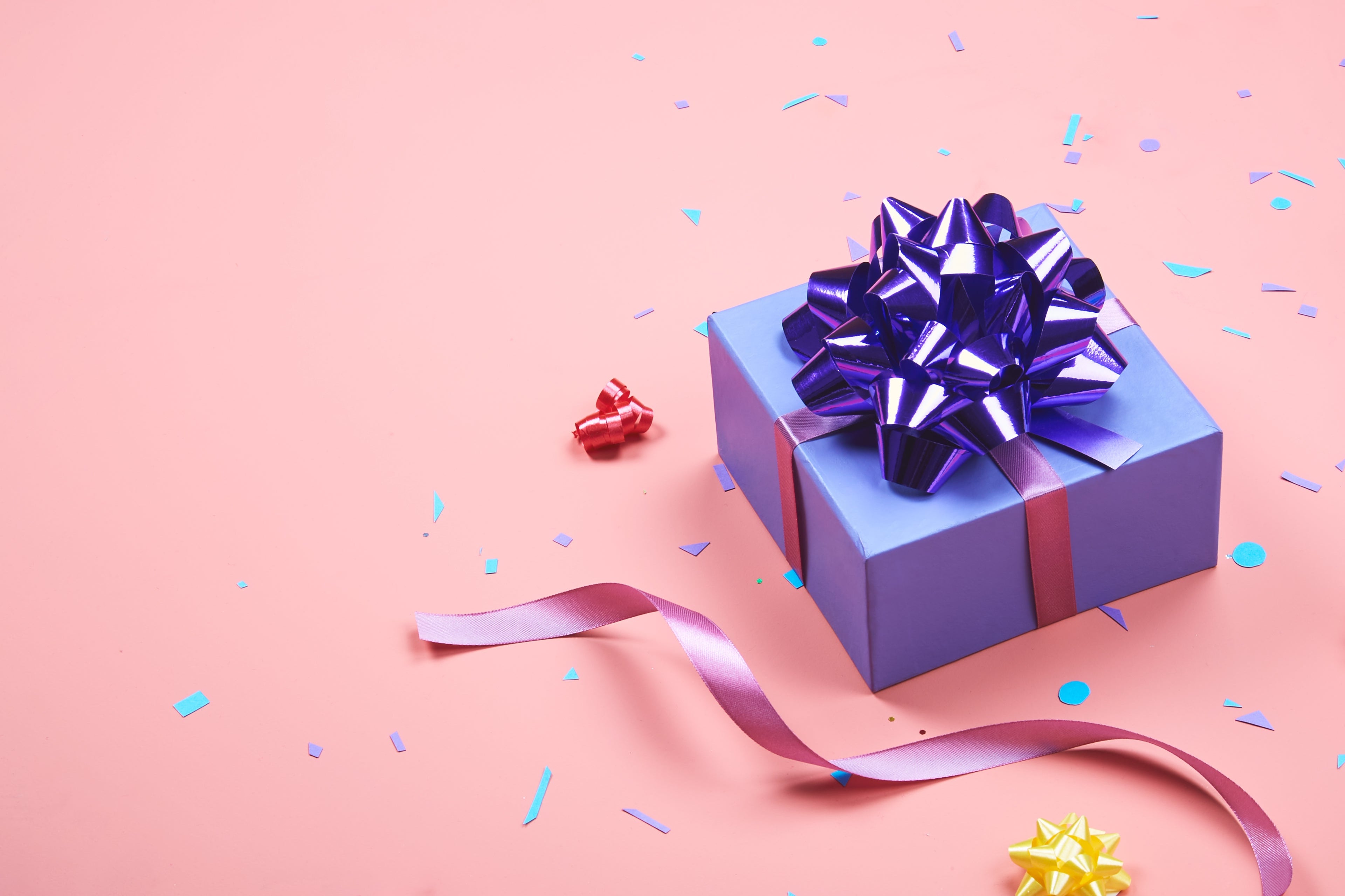 Blue gift box with a purple bow on a pink background